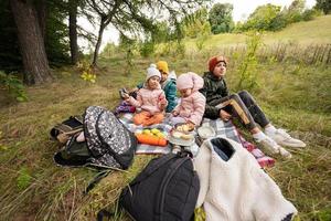 picnic nel autunno parco. quattro bambini mangiare nel il foresta, mentre seduta su lenzuolo. foto