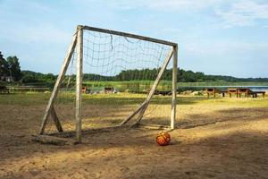 calcio obbiettivo e palla su il spiaggia. luce del sole, acqua e sabbia. il spiaggia su il lago di il turista base. foto