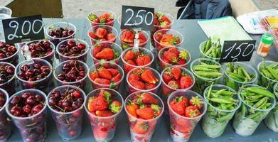 tazze con frutti di bosco per vendita nel il parco, ciliegie, piselli, fragole, il prezzo di frutti di bosco, strada commercio nel estate foto