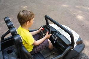 carino europeo ragazzo cavalcate un' figli di auto nel il parco, figli di cavalcate, parco intrattenimento, figli di elettrico auto foto