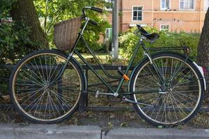 elegante verde Vintage ▾ retrò bicicletta con di vimini cestino parcheggiata nel il città foto