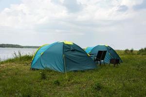 turista tende per campeggio su il lago costa, viaggio storia. pesca, turismo, attivo ricreazione. naturale paesaggio. per stile di vita design. all'aperto ricreazione foto