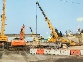 costruzione di un' rotto ponte su un' occupato strada. costruzione attrezzatura su un' sezione di il strada erige un cavalcavia. Il prossimo per un' plastica barriera di bianca e rosso colore foto