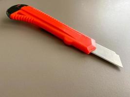 rosso acuto ufficio Stazionario coltello con un' carta taglio lama su un' del desktop ufficio scrivania. attività commerciale opera foto