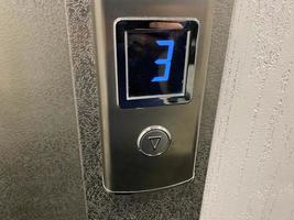 metallico brillante cromo plated moderno ascensore chiamata pulsante con pavimento designazione Schermo nel moderno edificio foto