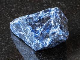 crudo sodalite pietra preziosa su nero granito foto