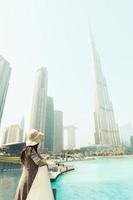 dubai, Emirati Arabi Uniti, 2022 -moderno turista femmina viaggiatore guardare a burj khalifa Torre contro nebbioso bianca cielo, dubai, Emirati Arabi Uniti foto