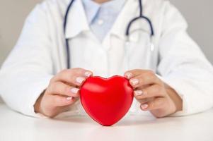 irriconoscibile medico Tenere cuore su tavolo. organo donazioni, beneficenza, cardiologia concetto foto