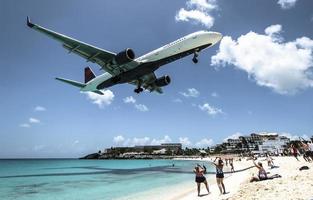 st. Martin, 2013 - i turisti affollano la spiaggia di Maho mentre un aereo a bassa quota si avvicina alla pista sopra il litorale foto