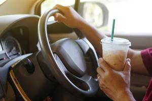 avvicinamento mano hold tazza di ghiacciato caffè per bevanda nel macchina. concetto, baverge per rinfrescante o porzione per sveglio a partire dal addormentato durante guida quello può causa auto incidente. foto