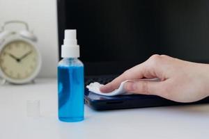 mano pulisce con un antibatterico antisettico disinfettante spray il computer portatile foto