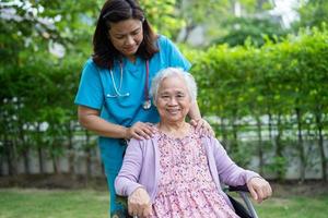 medico caregiver aiuto e cura asiatico anziano o anziano anziana donna paziente seduto su sedia a rotelle nel parco in ospedale di cura, sano concetto medico forte foto