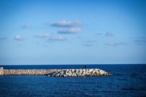 cemento frangiflutti con calma mare e blu cielo. orizzontale Immagine. foto