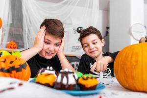 bambini avendo divertimento per Halloween circondato con pauroso decorazione. Jack o' lanterna Halloween zucca e cupcakes su il tavolo. contento Halloween foto