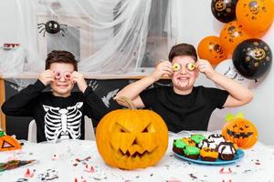 contento Halloween attraente giovane ragazzo con il suo grande fratello siamo preparazione per Halloween festa. fratelli nel costumi siamo avendo divertimento e giocando con pauroso occhi decorazione foto