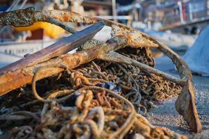 vecchio arrugginito ancora su il ancora vecchio catena nel il marina di il città nel il raggi di il crescente sole. molo a il yacht club, selettivo messa a fuoco, sfondo o schermo di mare vacanza e viaggio foto