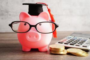 salvadanaio con occhiali con monete e calcolatrice concetto di educazione della banca di risparmio. foto