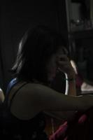 un' silhouette asiatico ragazza vicino su nel il buio camera essere triste e depresso solo, un' triste donna seduta solo, cuore rotto asiatico ragazza. foto