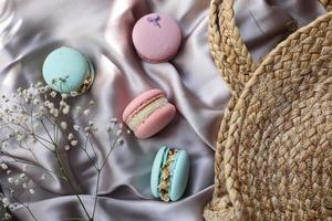 amaretti francesi rosa e menta o biscotti macarons e fiori bianchi su uno sfondo di stoffa. aromi naturali di frutta e bacche, ripieno cremoso per san valentino festa della mamma pasqua con cibo d'amore foto