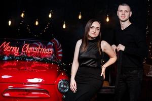 giovane contento coppia uomo e donna nel amore nel Natale siamo abbracciare vicino un' rosso retrò auto con nuovo anni i regali. bacio, ragazza, felicità, quarantena Natale celebrazione, vacanza foto