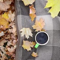 autunno le foglie e caldo cottura a vapore tazza di caffè bugie su scacchi plaid all'aperto foto