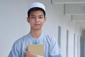 ritratto giovane sud-est asiatico islamico o musulmano ragazzo nel bianca camicia e cappello, isolato su bianca, morbido e selettivo messa a fuoco. foto