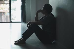 schizofrenia con solitario e triste nel mentale Salute depressione concetto. depresso donna seduta contro parete a casa con un' ombra su parete sensazione miserabile. donne siamo depresso, pauroso e infelice. foto