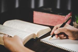 giovane donna persona mano Tenere santo Bibbia con studia a casa. adulto femmina cristiano lettura libro nel Chiesa. ragazza apprendimento religione spiritualità con pregare per Dio. concetto di alunno formazione scolastica fede. foto