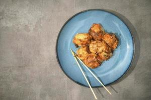 tradizionale giapponese cibo, takoyaki con salsa su un' blu piatto foto