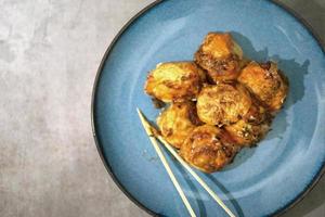 tradizionale giapponese cibo, takoyaki con salsa su un' blu piatto foto