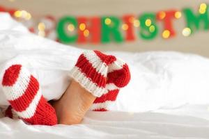 bambini spoglio piedi vicino su e lana a maglia rosso bianca calze.festive mood.christmas concetto, vacanza.felice nuovo anno.bambino ragazza sotto bianca soffice coperta foto