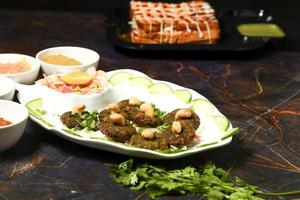 indiano lato piatto popolare chaat spuntini aloo aalù schiacciato bollito Patata tikki con speziato verde chutney e pomodoro salsa foto