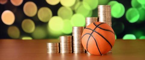 pallacanestro e pile di d'oro monete nel crescita grafico su il sfocato bokeh sfondo foto