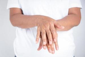 anziano donna nel bianca Abiti lavare loro mani con alcool gel. impedire infezione a partire dal il coronavirus. concetto di protezione contro covid-19 virus foto