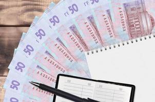50 ucraino grivna fatture fan e bloc notes con contatto libro e nero penna. concetto di finanziario pianificazione e attività commerciale strategia foto