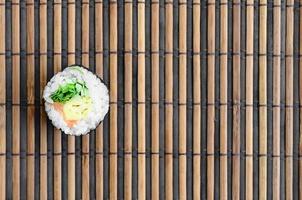 Sushi rotolo menzogna su un' bambù cannuccia servire stuoia. tradizionale asiatico cibo. superiore Visualizza. piatto posare minimalismo tiro con copia spazio foto