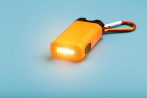 un arancia guidato torcia elettrica con un' moschettone si illumina su un' blu sfondo. foto