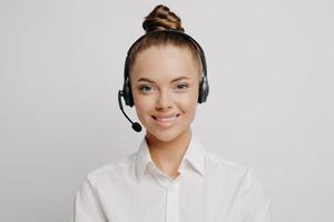 femmina chiamata centro lavoratore nel bianca camicia sorridente a telecamera foto