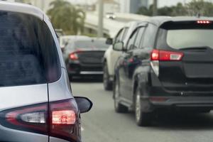 posteriore lato di argento auto su il asfalto strada girare su freno leggero e intestazione in direzione il obbiettivo di il viaggio. in viaggio per opera durante corsa ora. ambiente sfocato di altro macchine durante il giorno. foto