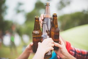 gruppo di uomo e donna godere campeggio picnic e barbecue a lago con tende nel sfondo. giovane misto gara asiatico donna e uomo. giovane persone mani tostatura e applauso birra. Vintage ▾ filtrato Immagine foto