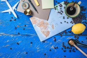 concetto di viaggio utilizzando la mappa del mondo e la bussola insieme ad altri accessori da viaggio. tazza di caffè e chicchi di caffè tostato foto