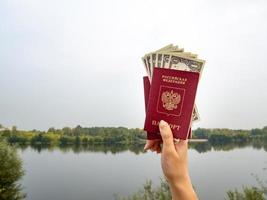 un passaporto straniero e dollari in mano, sullo sfondo della natura. foto