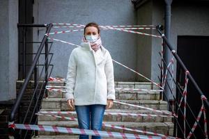 foto di una ragazza in maschera. in piedi per strada con nastri di avvertimento di pericolo.