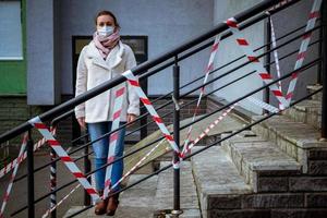 foto di una ragazza in maschera. in piedi per strada con nastri di avvertimento di pericolo.