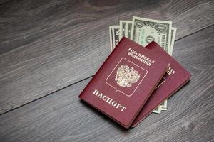 un passaporto straniero e dollari su uno sfondo di legno. foto