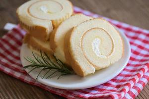 torta rotolo su piatto torta con rosmarino su tavolo, spugna torta rotolo fette dolci dolce crema rotolo vaniglia spuntini e cibo concetto - svizzero rotolo torta foto