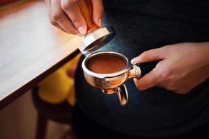 avvicinamento di mano barista bar fabbricazione caffè con Manuale presse terra caffè utilizzando manomettere a il caffè negozio foto