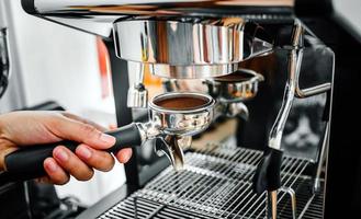 avvicinamento di mano barista fabbricazione fresco caffè processi di preparazione caffè tavoletta prima installazione esso in il caffè macchina foto