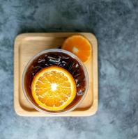 ghiacciato caffè bevanda menù arancia Americano fusione con fresco arancia frutta misto nel un' plastica tazza, bevanda menù Prodotto. foto