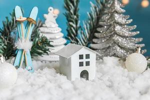 sfondo astratto di natale di avvento. giocattolo modello casa e decorazioni invernali ornamenti su sfondo blu con neve. natale con la famiglia a casa concetto. foto